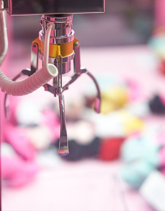 Close-up of a claw machine crane over plush prizes at Starrcade Kennesaw